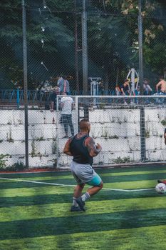 Man playing football on a vibrant urban soccer field, seen from behind.