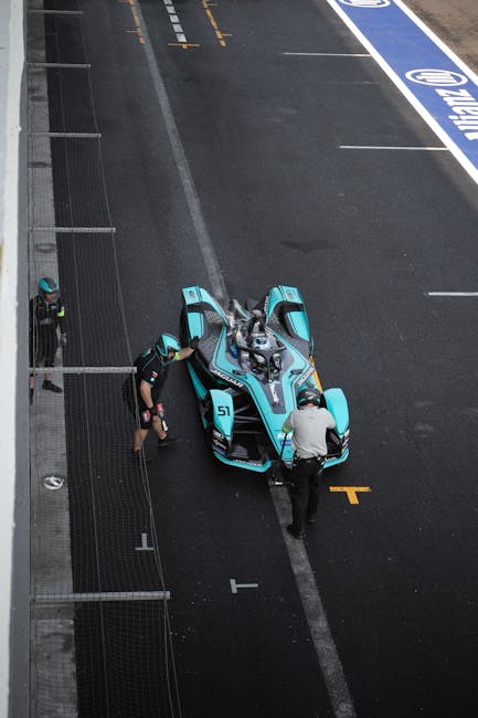 A Formula E race car in a pit stop with crew at Ciudad de México race track.