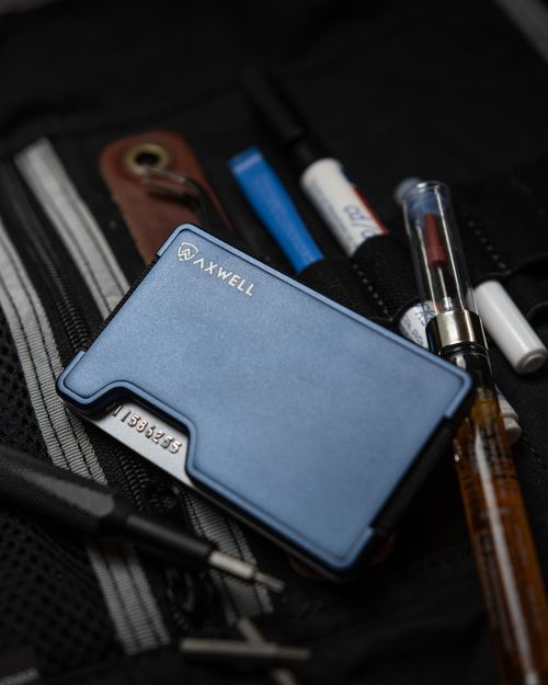 Free Close-up of a sleek blue wallet with various pens and accessories on a black surface. Stock Photo