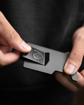 Close-up of hands holding a sleek minimalist metal wallet.