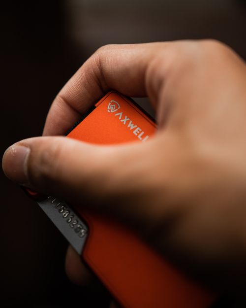 Free A close-up of a hand holding an orange wallet, showcasing style and functionality. Stock Photo
