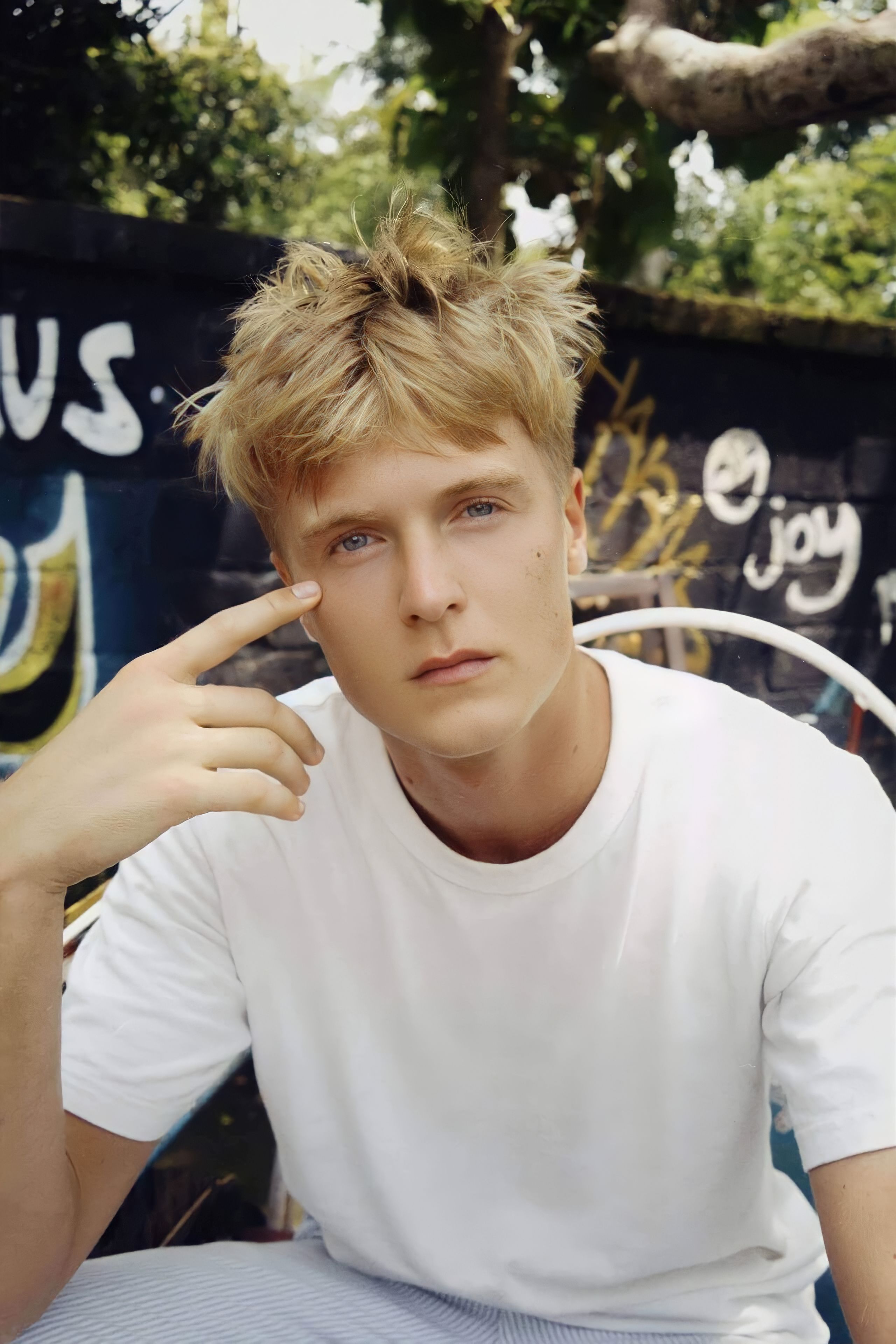 Casual portrait of a young man outdoors against graffiti wall in Ciudad de México.