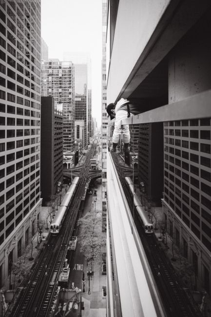 Black and white view of a daring climber in a cityscape between skyscrapers.