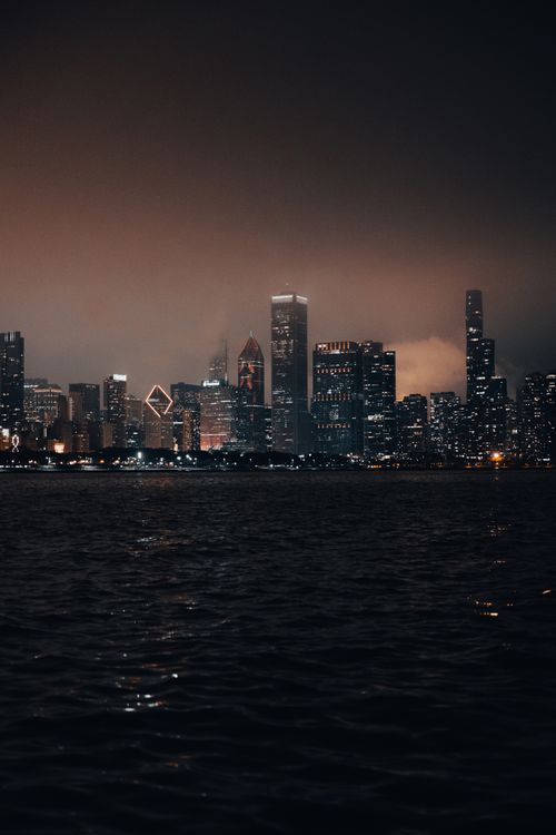 Free Beautiful illuminated city skyline at night with reflections on water, showcasing a vibrant urban atmosphere. Stock Photo