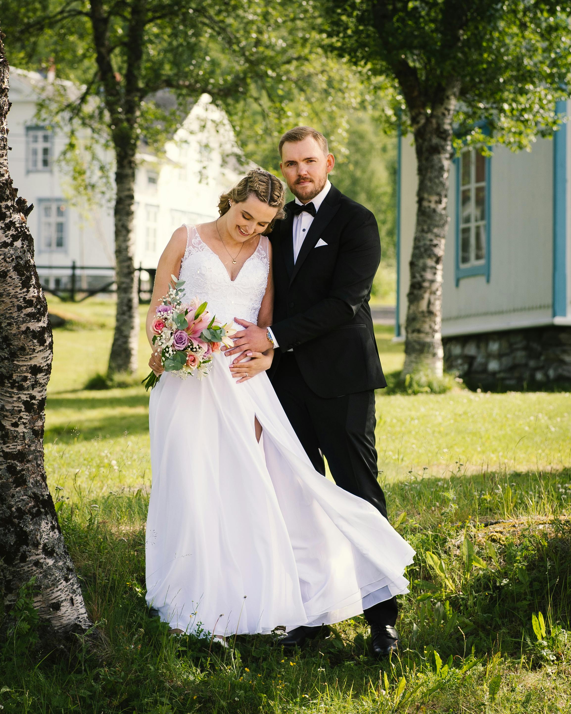 a bride and groom standing together on green grass field