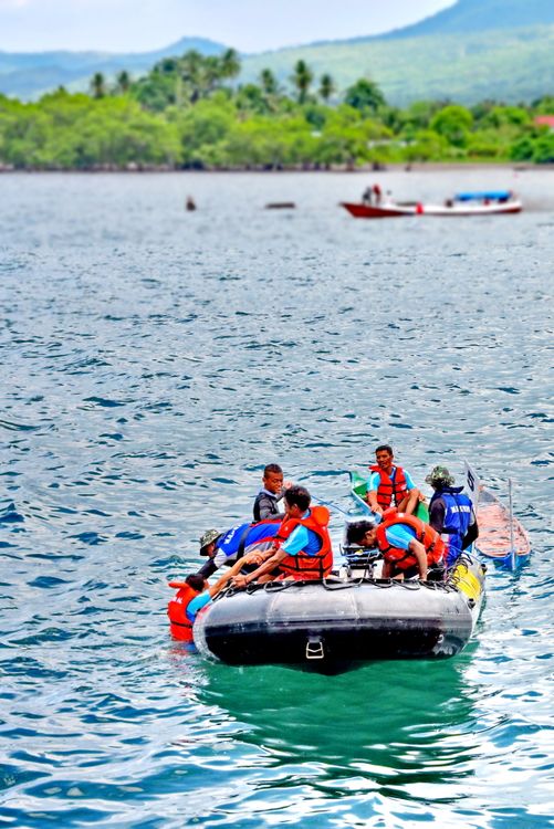 A Group of People Riding a Boat Recuing a Person in Body of Water ...