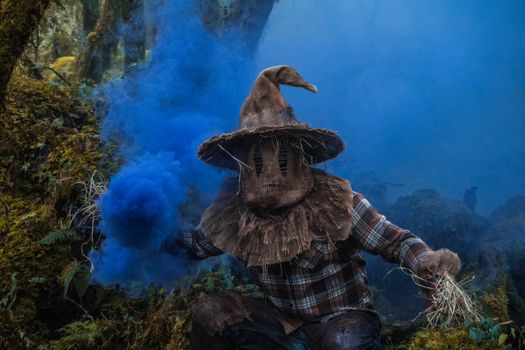 A mysterious scarecrow releases blue smoke in a misty forest in Choachí, Colombia.