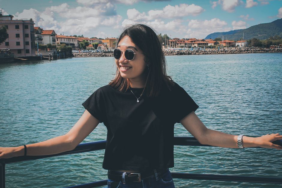 Woman smiling on a seaside railing with a scenic view in Siviano, Italy.
