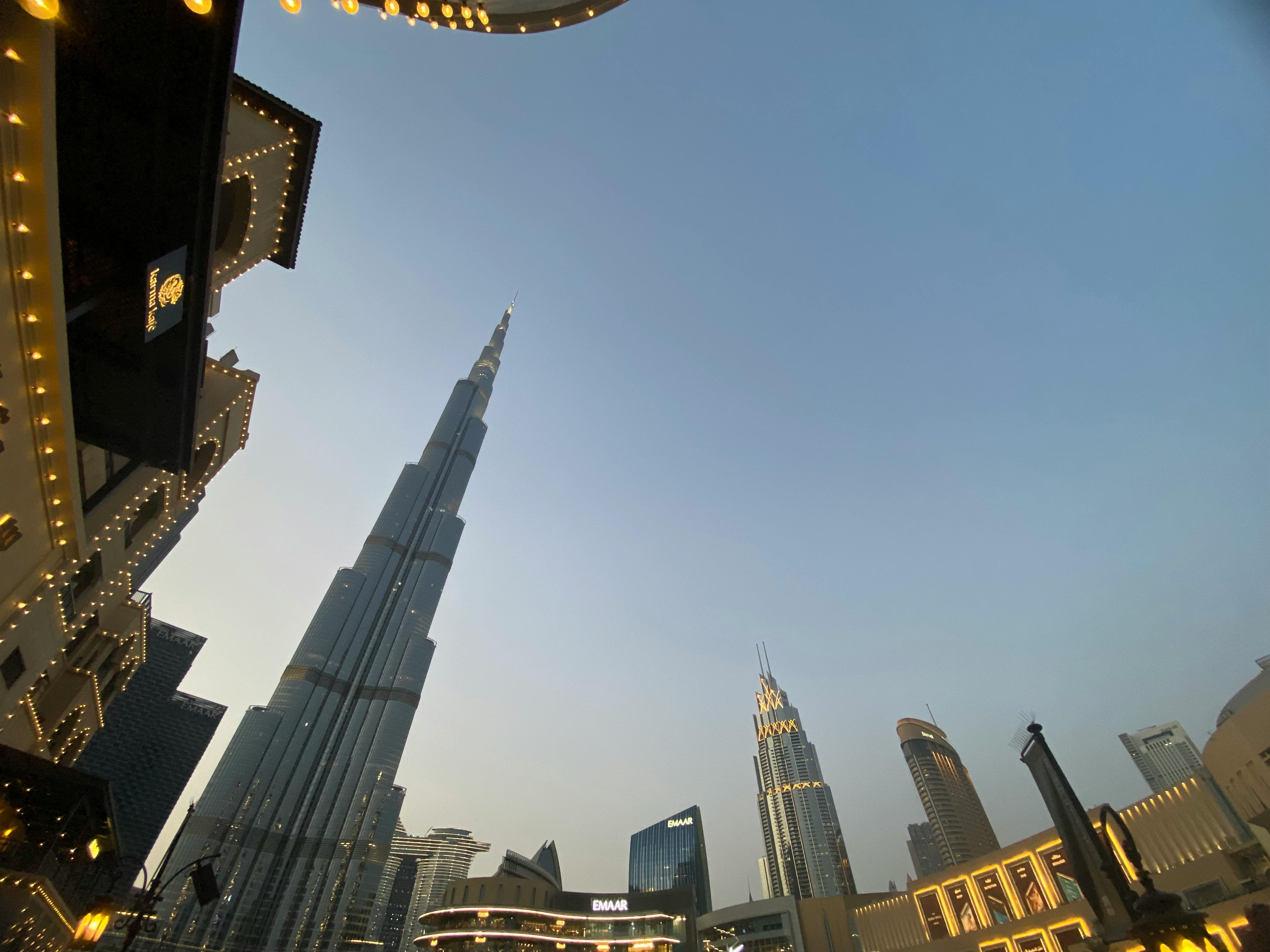 Low-angle view of the Burj Khalifa amidst Dubai's urban skyline at dusk.