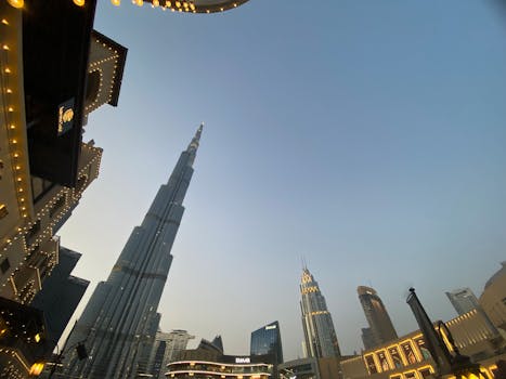 Low-angle view of the Burj Khalifa amidst Dubai's urban skyline at dusk.