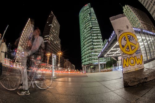 Man Riding Bicycle on Sidewalk Near Buildings during Nighttime