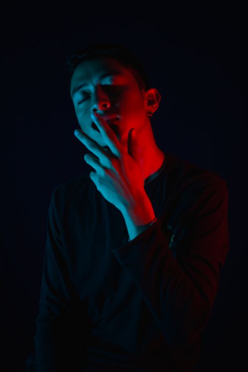 Free Artistic portrait of a person in red and blue lighting on a dark background. Stock Photo