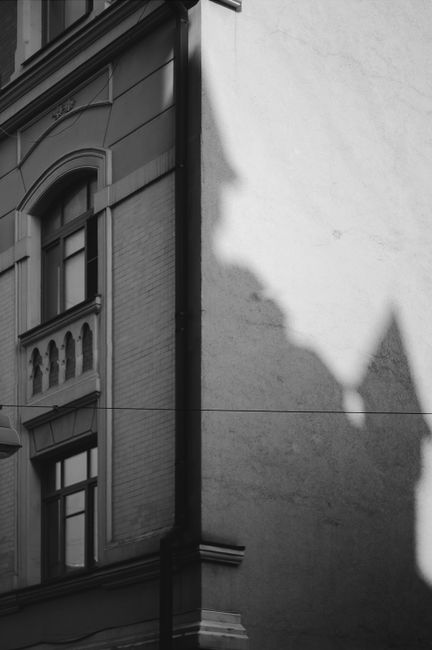 Monochrome image of a building facade with a dramatic shadow cast on the wall.