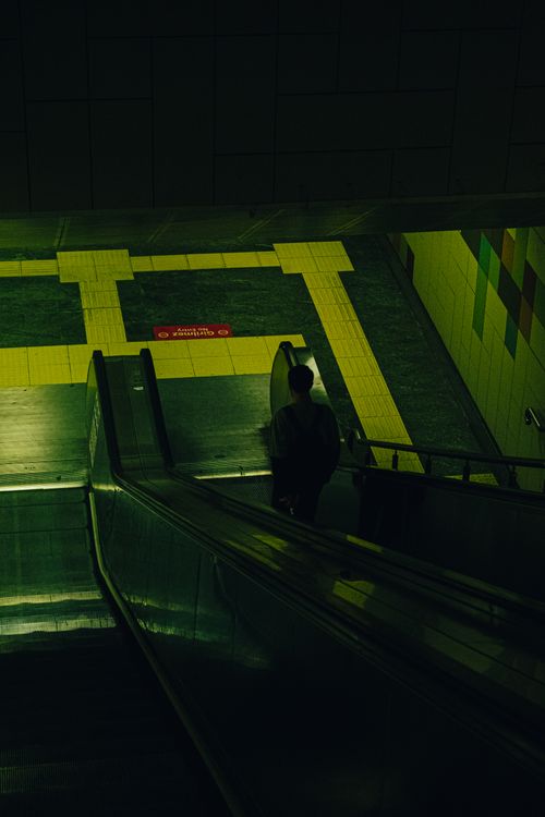 Free Silhouette of a person on an urban subway escalator with moody lighting. Stock Photo