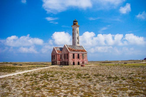 A Lighthouse Between Concrete Houses On the Middle of a Field Under Blue Sky