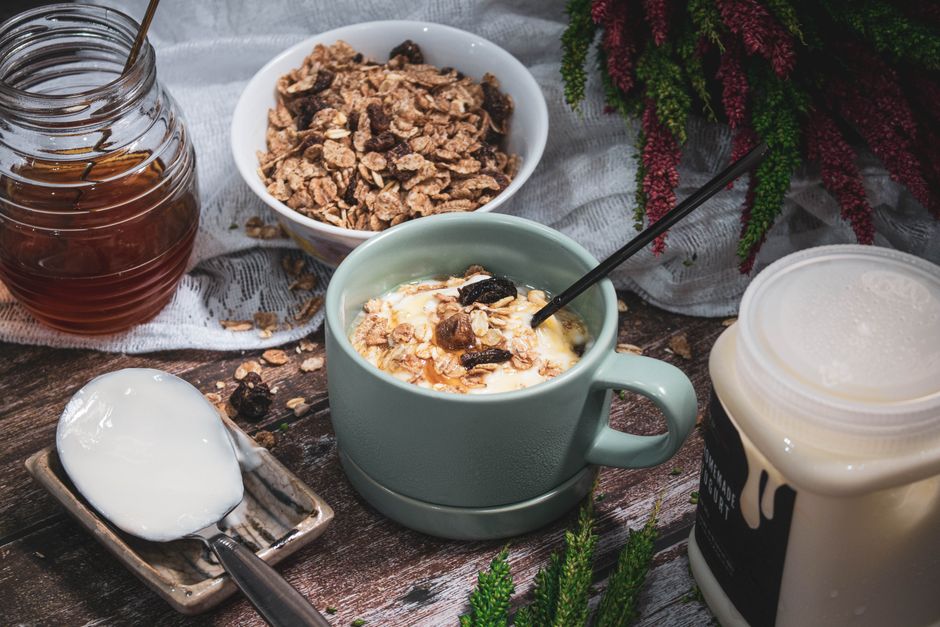 A cozy breakfast setup featuring cereal, honey, and yogurt on a rustic wooden table.