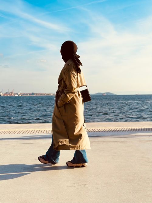 Free A woman in a trench coat walks along the Bosphorus in Istanbul under a clear sky. Stock Photo