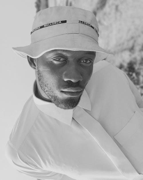 Grayscale Photography of a Man Wearing Bucket Hat while Seriously Looking at the Camera