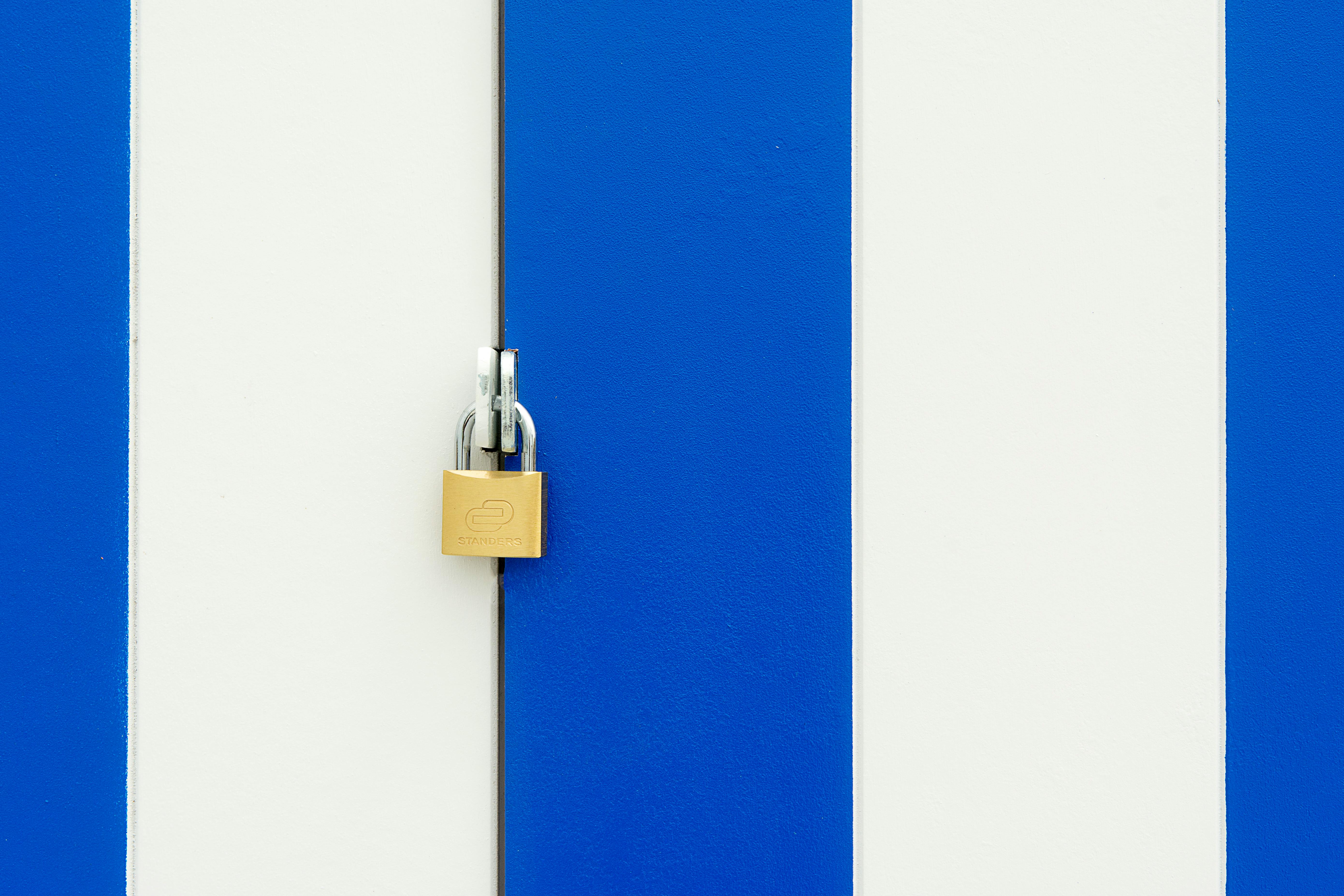 Padlock securing a blue and white striped door, symbolizing safety.