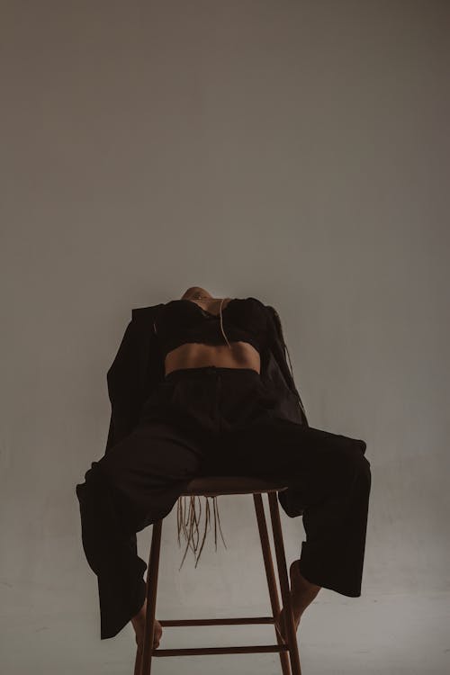 A Person in Black Bra and Brown Pants Sitting on a High Chair