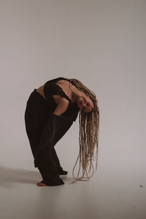 A Woman Wearing Lace Top and Black Blazer Bending Her Body while Posing at the Camera