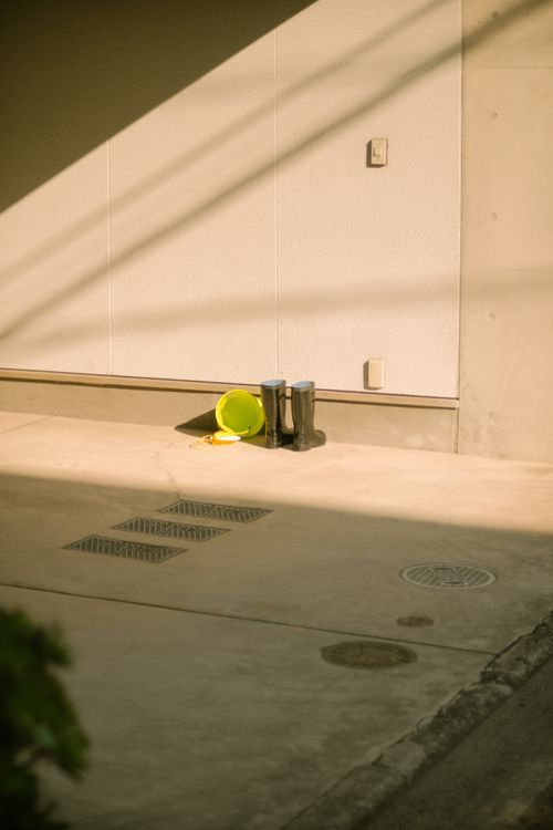 Free Minimalist urban scene of boots and yellow bucket against white wall with shadows. Stock Photo