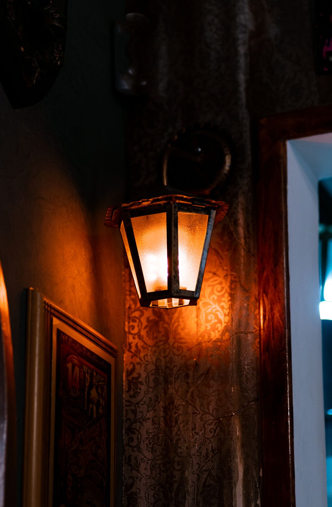 A lantern sconce glowing on a panelled interior wall — photo by Wolf Art on Pexels
