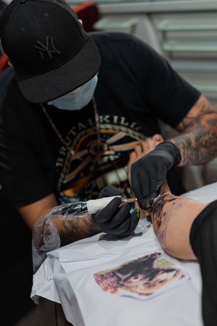 An Artist Tattooing Client's Leg