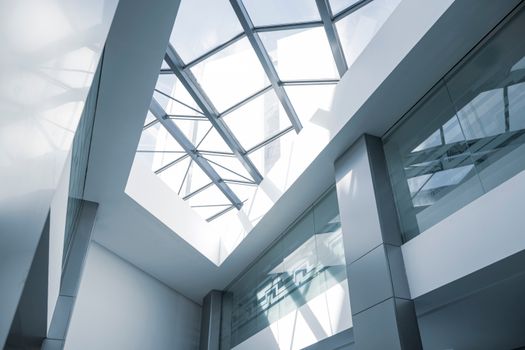 An interior look at a modern office building featuring a glass ceiling and sleek steel frames.