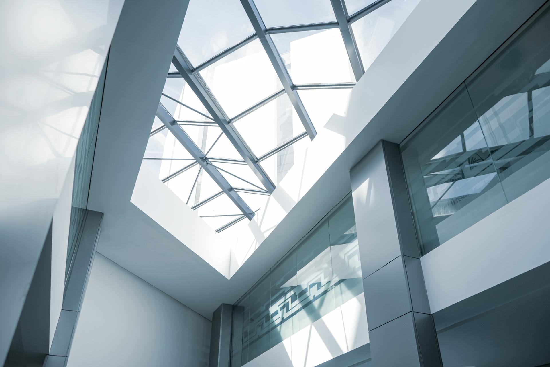 An interior look at a modern office building featuring a glass ceiling and sleek steel frames.