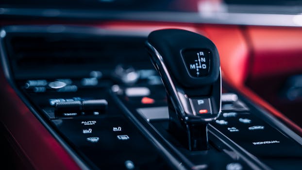 Detailed view of an automatic car gear shifter in a sleek car interior.