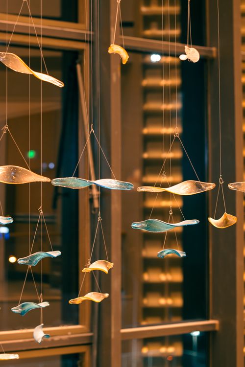 Free A decorative indoor hanging art installation with warm lighting and vertical elements. Stock Photo