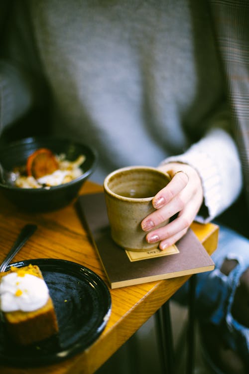 Free Person Holding Mug on Top of Brown Book Stock Photo