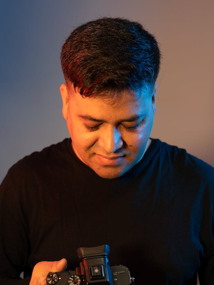 Smiling Man Using Professional Camera In Studio