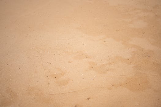 Close-up of smooth sandy beach surface in Albufeira, Portugal, capturing the natural texture and colors.