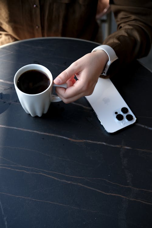 Person Holding Coffe Cup near Mobile Phone
