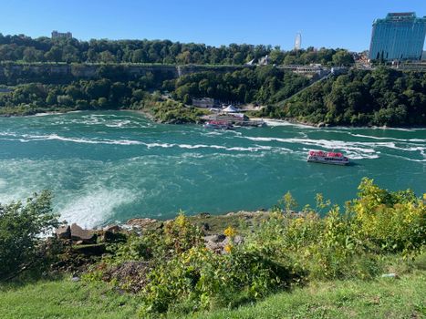 Beautiful scenery of Niagara River with ferries and lush forests in New York.