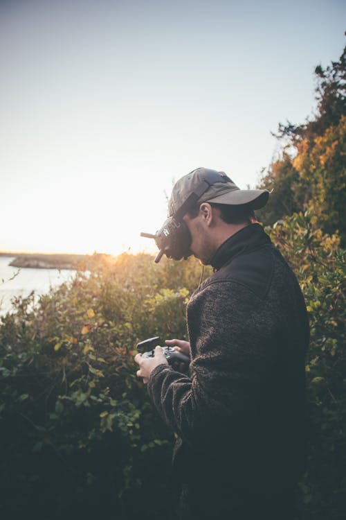 Man in Virtual Reality Goggles and with Drone Controller at Sunset