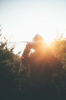 A person stands outdoors wearing virtual reality goggles against a sunset backdrop.