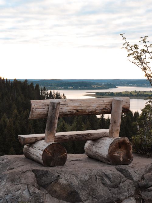 Free Rustic wooden bench on a rocky cliff with a serene lake view at sunset. Stock Photo