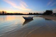 日落时分，平静的湖面上停着一艘船，映照着充满活力的天空和宁静的水域