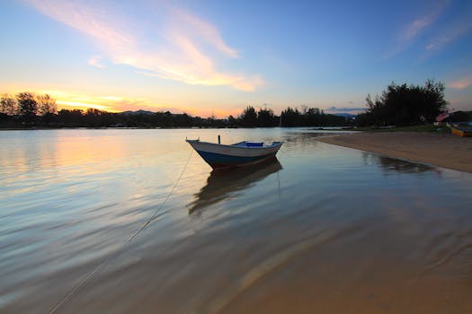 日落时分，平静的湖面上停着一艘船，映照着充满活力的天空和宁静的水域