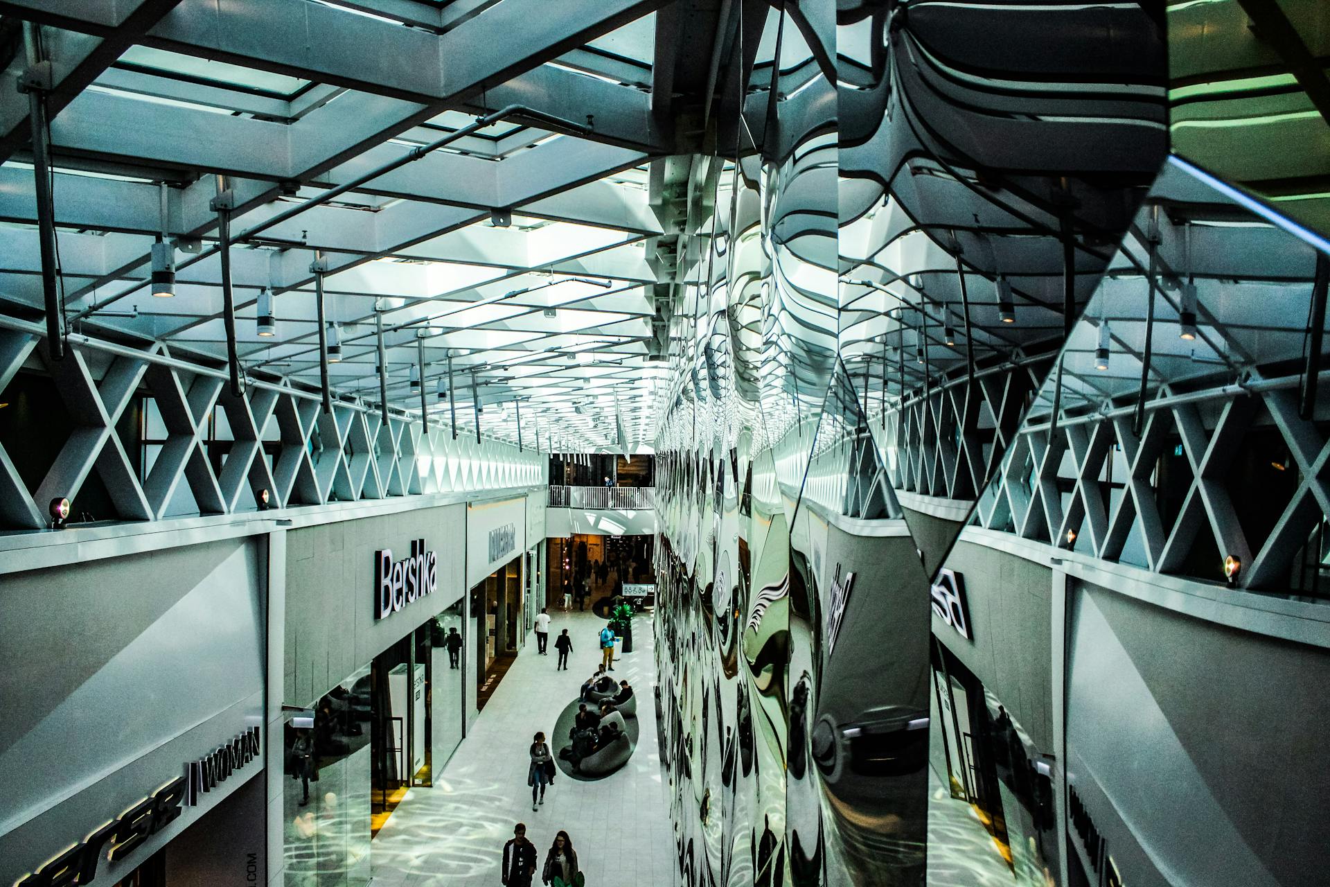 A contemporary shopping mall hallway with glass reflections and modern architecture.