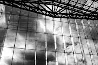 黑白照片中的现代玻璃建筑映照着天空和云层