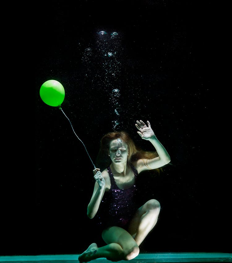 Underwater Photography Of Woman Holding Green Balloon