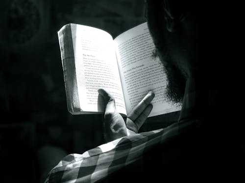 A Grayscale of a Bearded Man Reading a Book