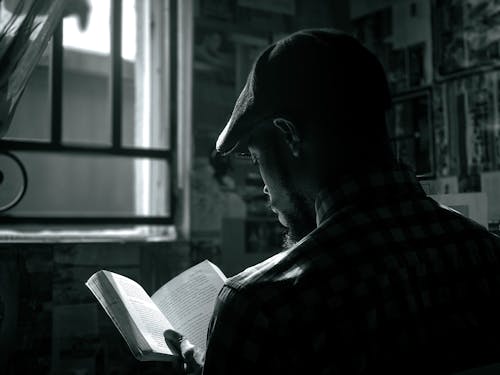 Monochrome Shot of a Man Reading a Book