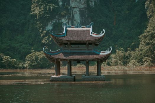 A serene floating pagoda amidst lush greenery on a calm Vietnamese lake.
