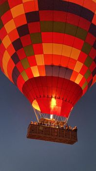 A vibrant hot air balloon soaring against a twilight sky with passengers enjoying the view.