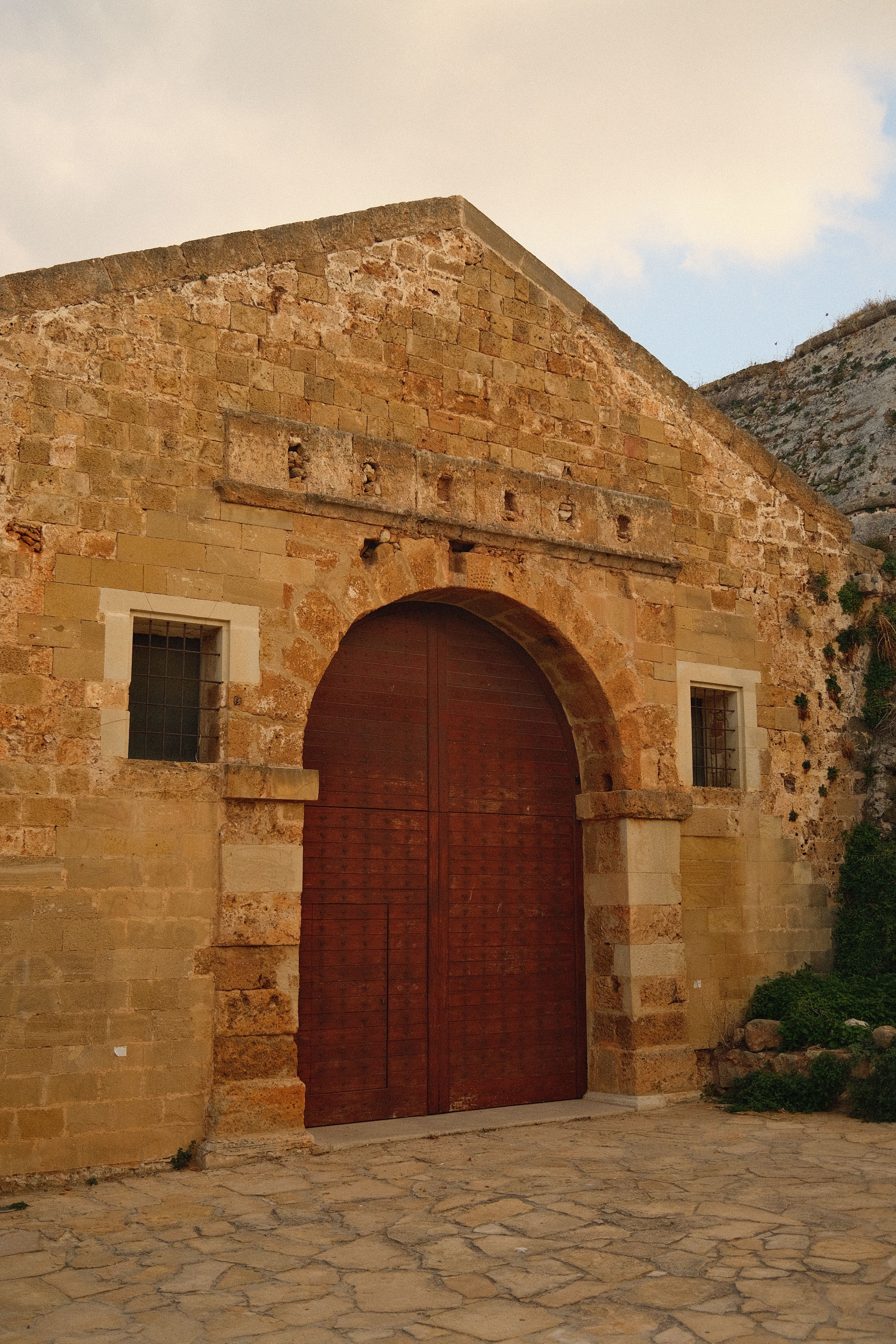 Explore a picturesque historic stone building with an arched wooden entrance.